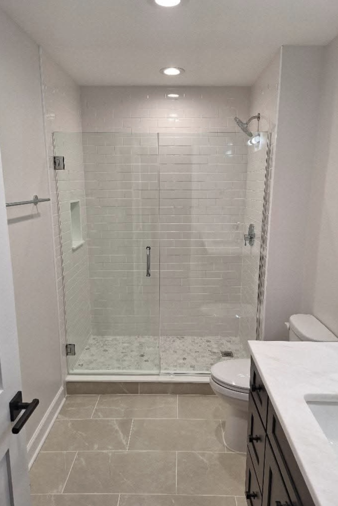 Remodeled bathroom with glass shower and subway tile