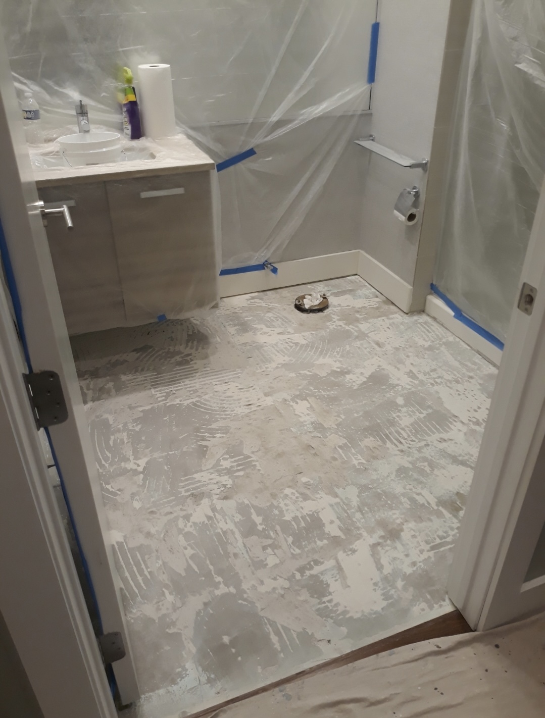 Clean, organized bathroom jobsite mid-renovation, subfloor exposed and protected